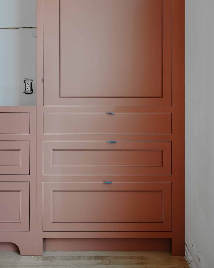 an empty room with pink cabinets and drawers on the wall, along with a wooden floor