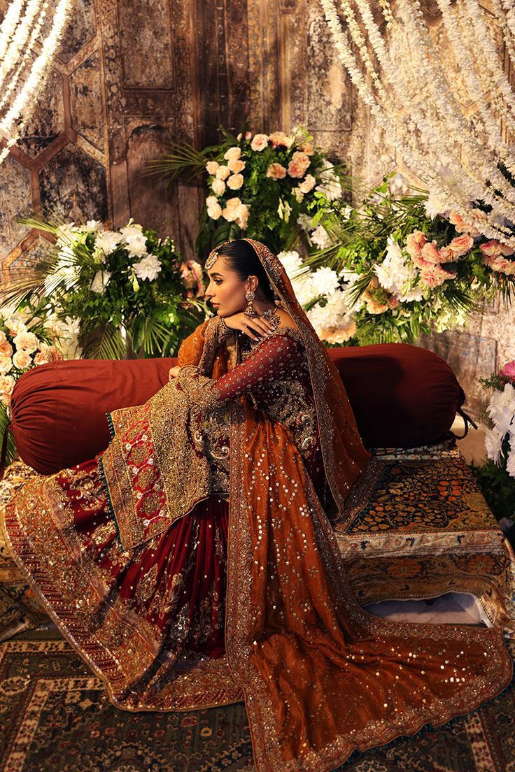 a woman sitting on top of a red couch in front of a flower covered wall