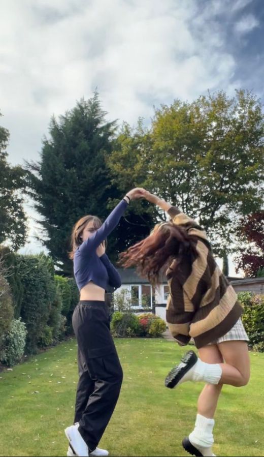 two young women are playing in the grass