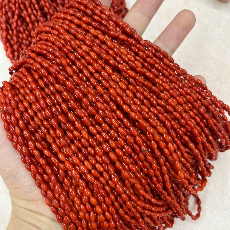 a hand is holding some red seed beads