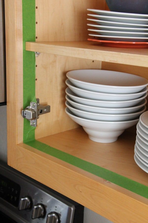 plates and bowls are stacked on top of each other in the kitchen cupboards,