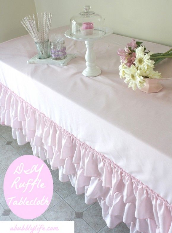 a pink table cloth with ruffled edges and flowers sitting on top of the table