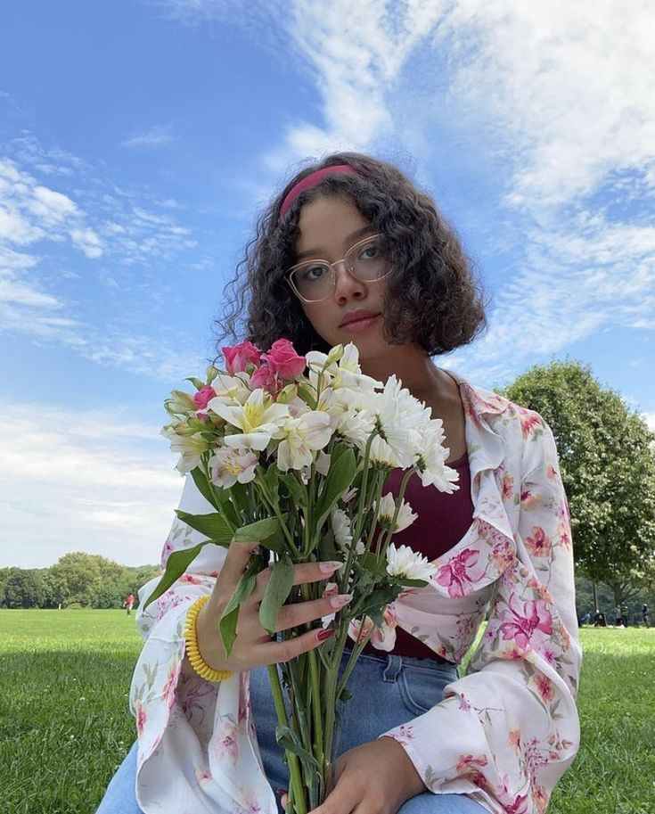 a woman sitting in the grass holding flowers