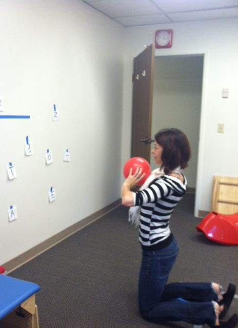 a woman holding a red frisbee while sitting on the floor in an office