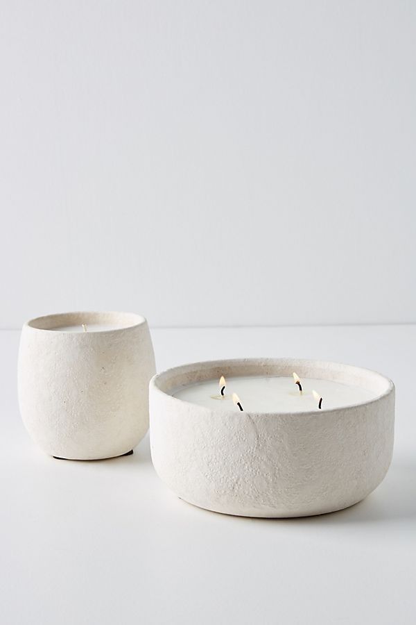 two white bowls sitting next to each other on top of a table with one candle in the middle