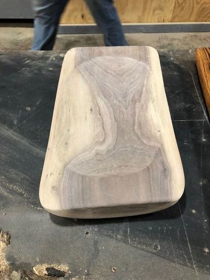 a wooden object sitting on top of a table next to a person's feet