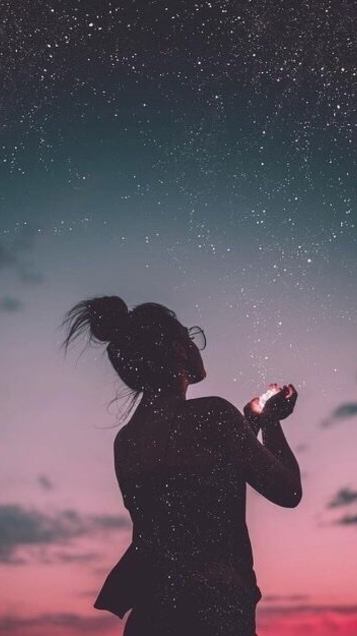 a woman looking up at the night sky with stars in her hair and holding a cell phone