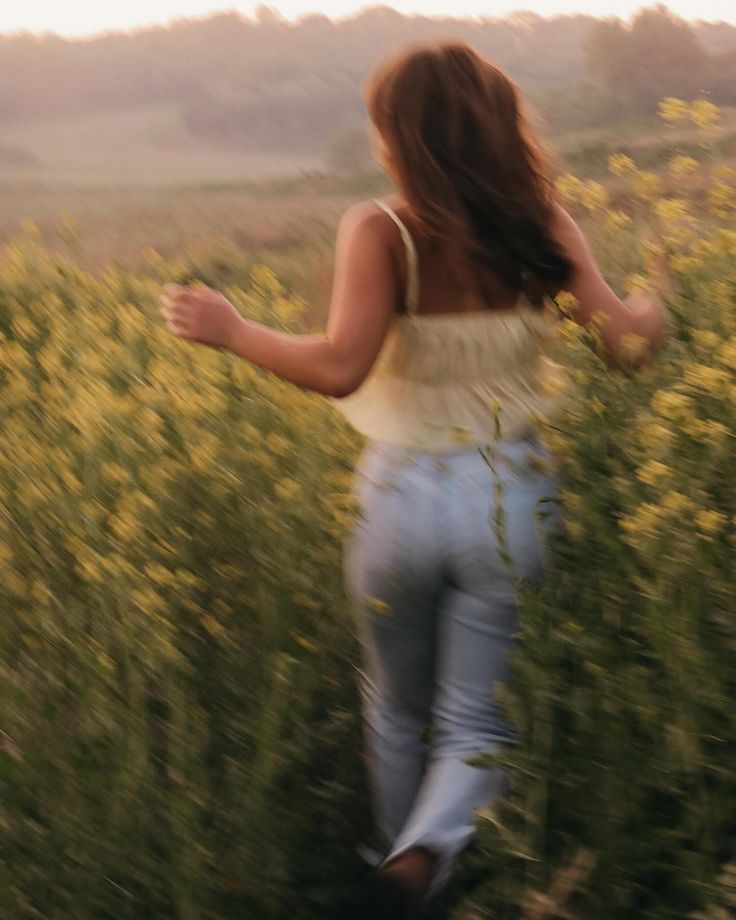 a woman is running through the tall grass