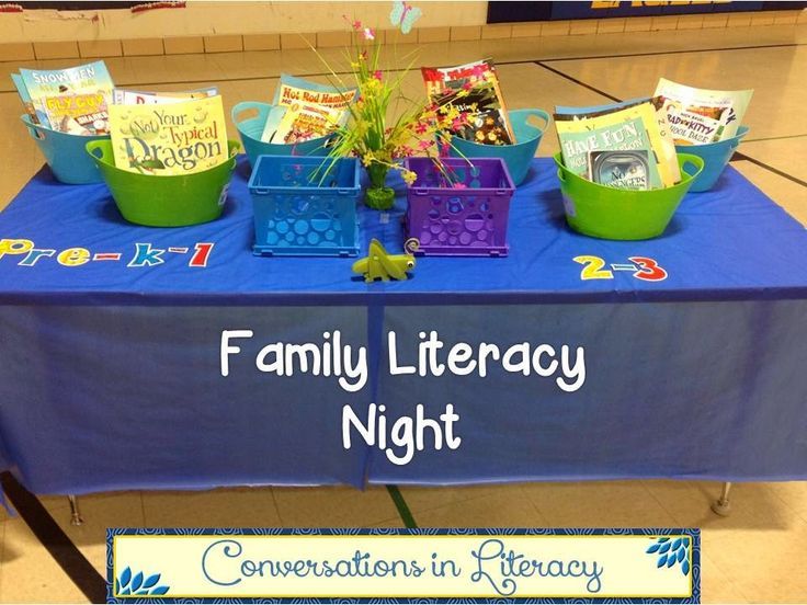 a blue table topped with green baskets filled with books and plants next to a sign that says family library night