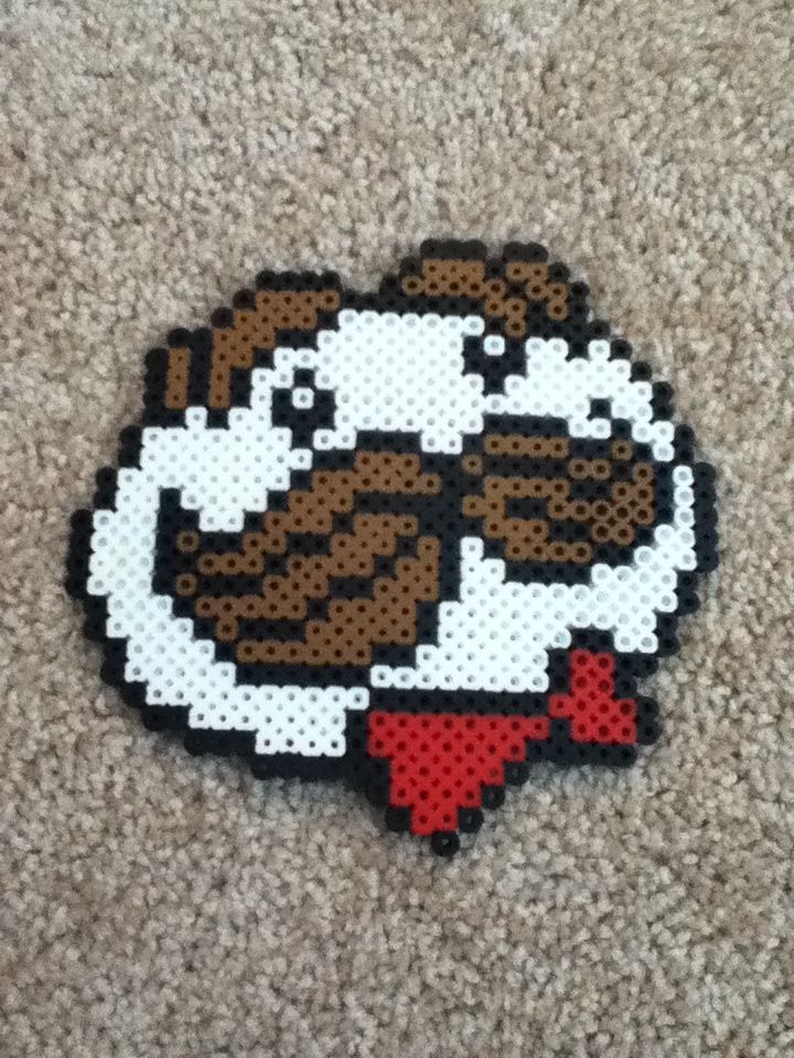 a piece of art made out of perler beads on carpeted area with brown and white dog