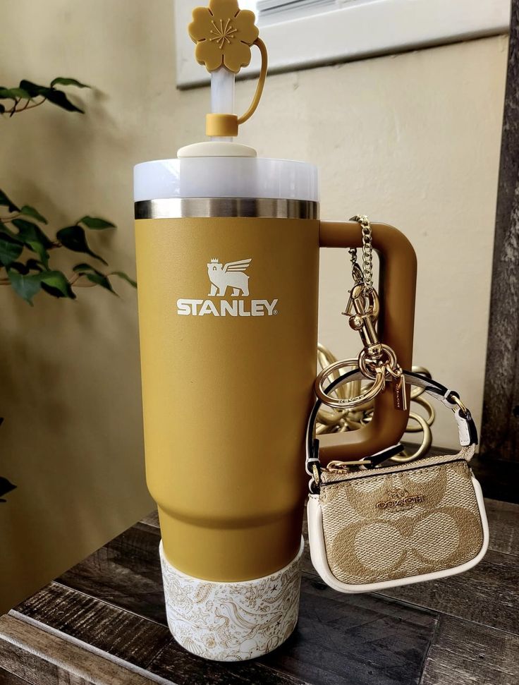 a starbucks cup with a keychain attached to it sitting next to a purse