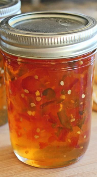 two jars filled with pickles sitting on top of a wooden table