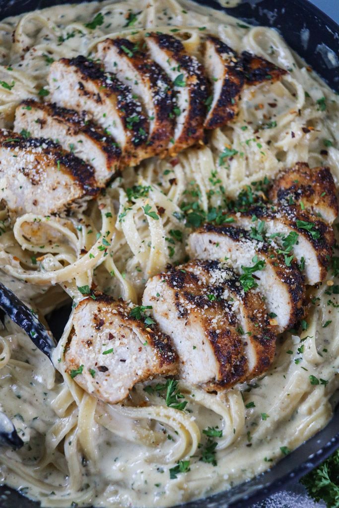 some chicken and noodles in a pan with parsley on the side for garnish