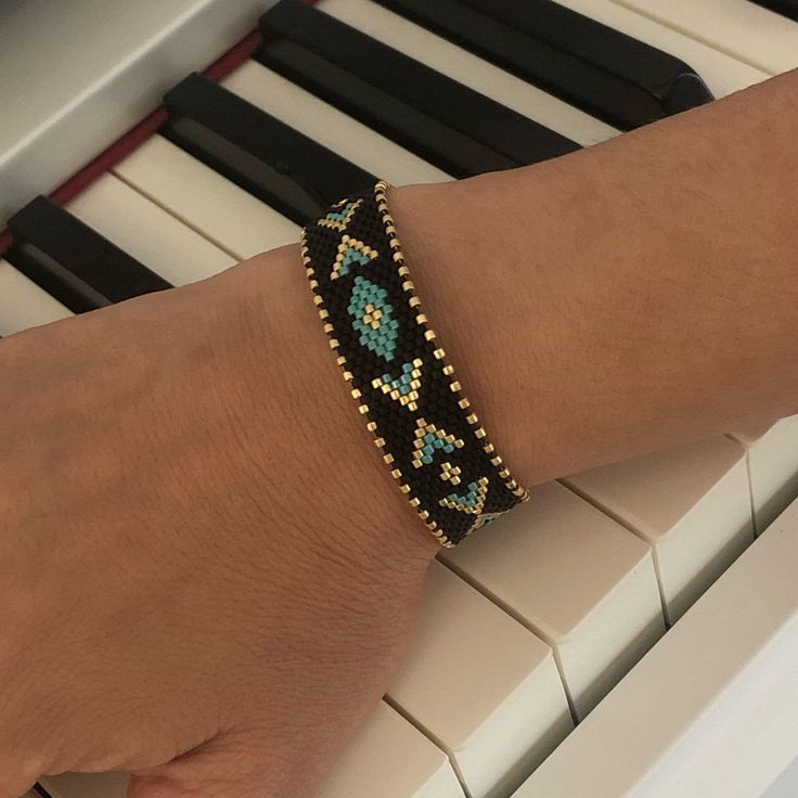 a person's arm with a bracelet on top of a piano keyboard and an electronic keyboard in the background