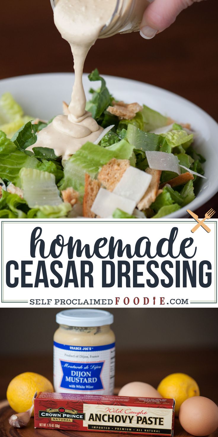 homemade caesar dressing being drizzled over a salad in a white bowl with lemons on the side