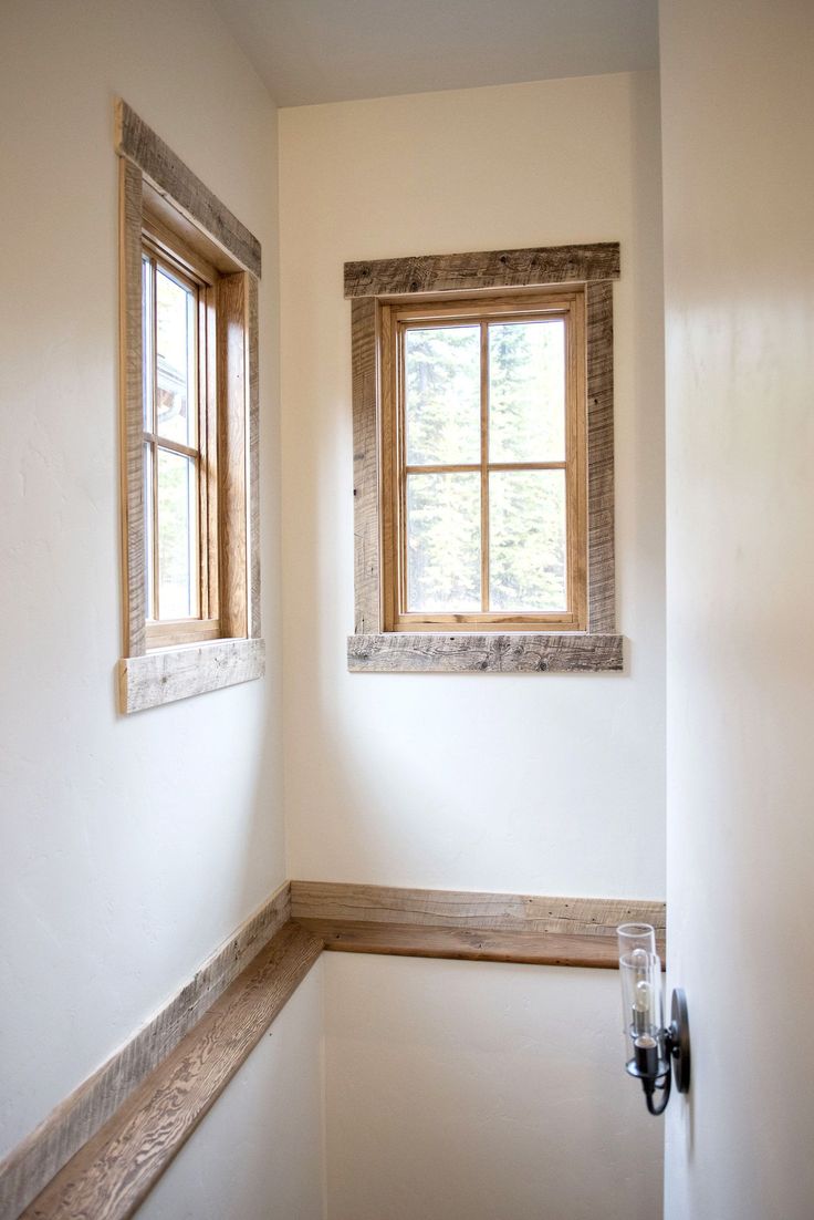 the corner of a room with a window and wooden trim on the wall next to a door