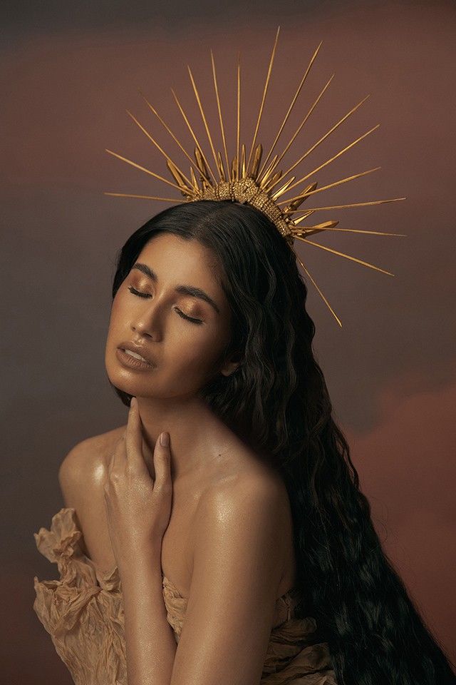 a woman with long hair and a crown on her head is posing for the camera