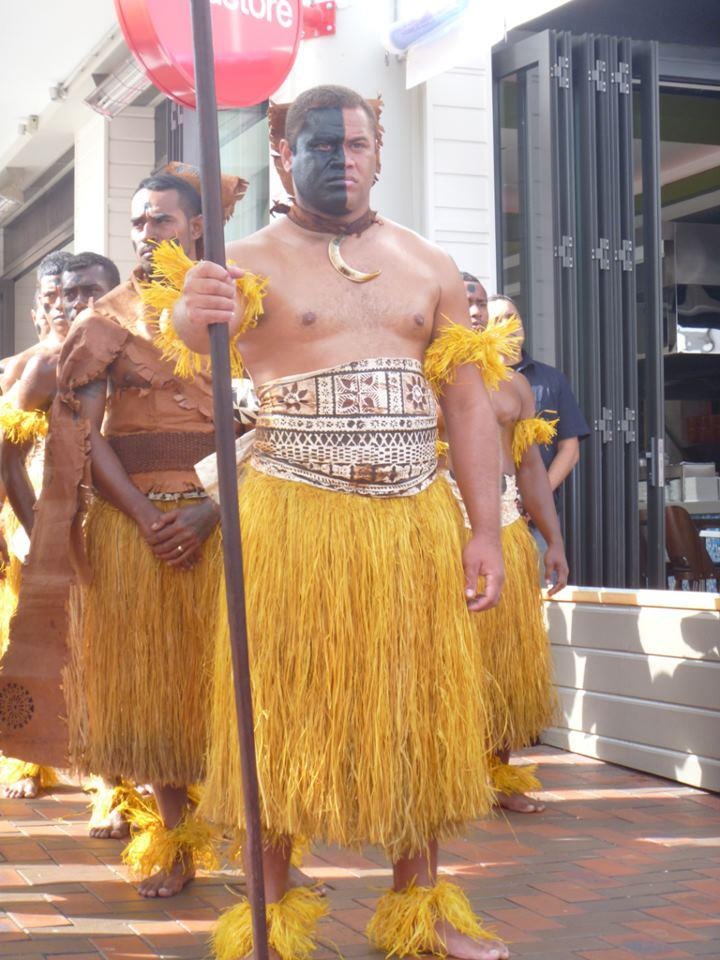 men in yellow hula skirts walking down the street with one holding a stop sign