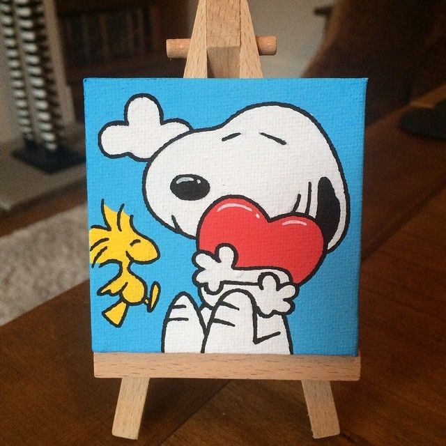 an easel with a painting of a cartoon character holding a heart in it's mouth