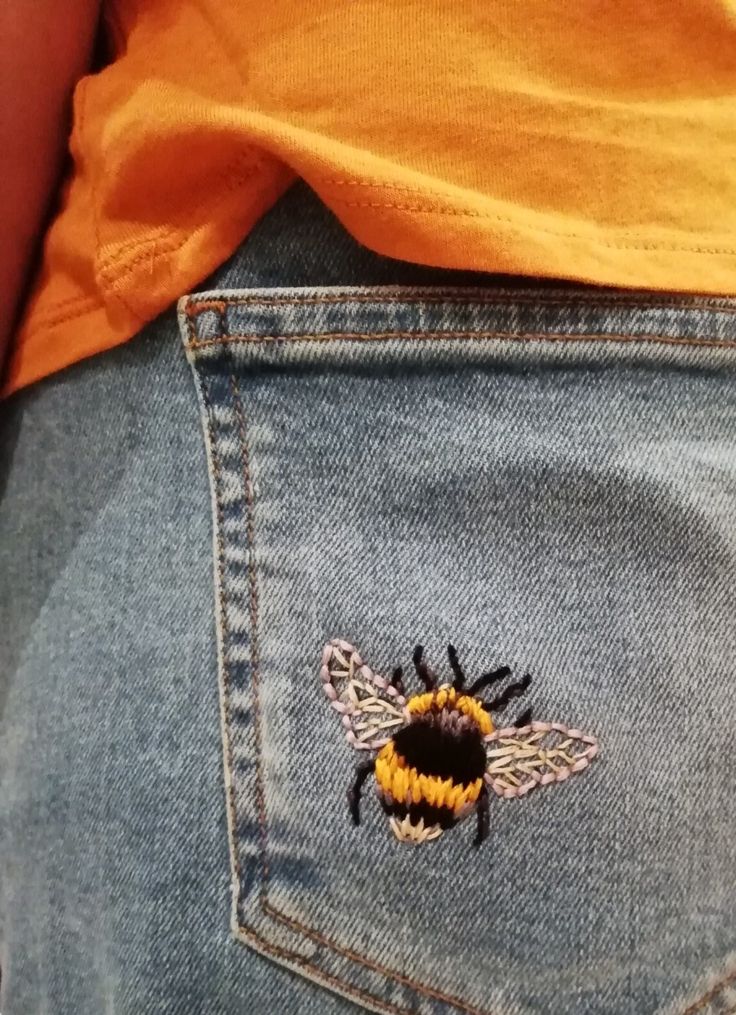 a close up of a person's jeans with a bee embroidered on it