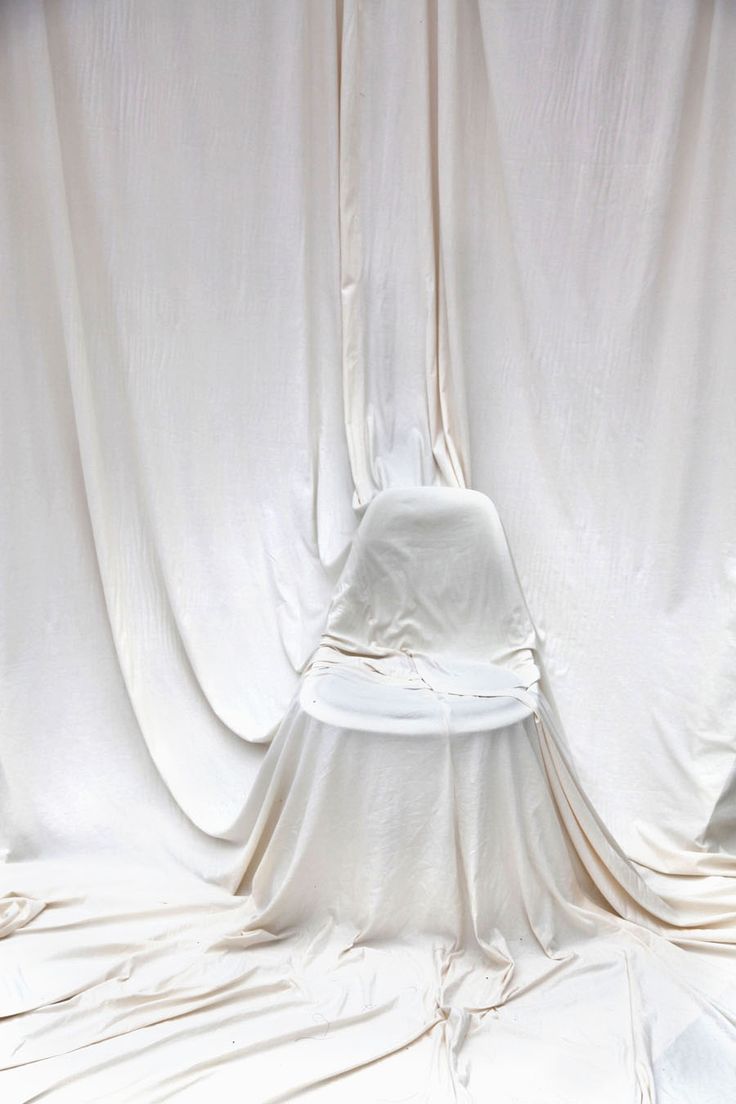 a white hat sitting on top of a table next to a curtain covered wall and floor