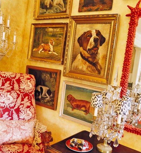 a living room filled with pictures and paintings next to a table topped with a red plate