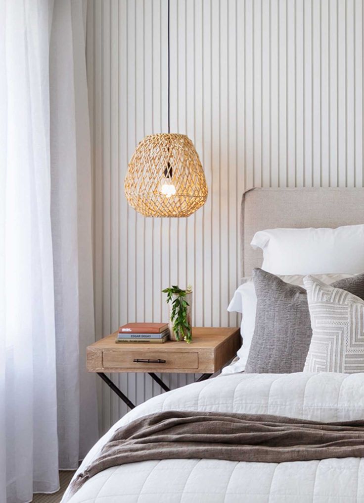 a bedroom with a bed, nightstand and lamp in the corner on the wall next to the window