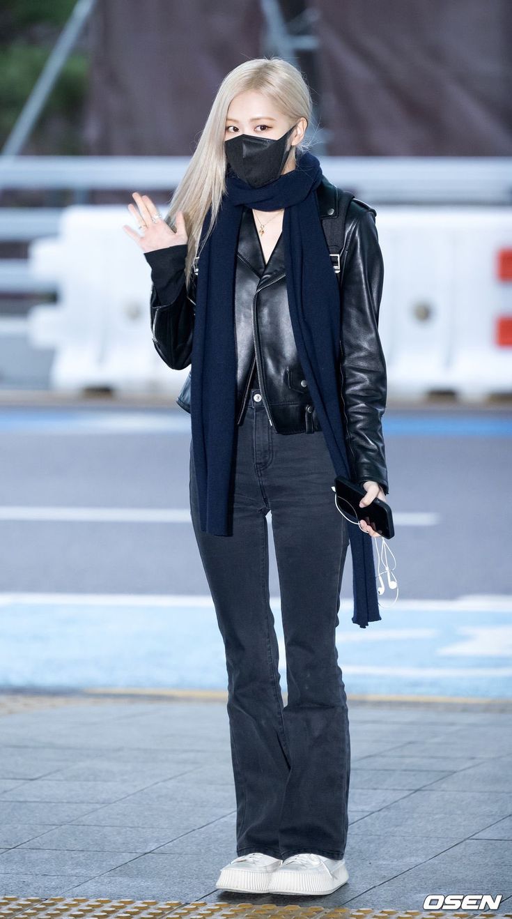 a woman wearing a face mask while standing on the sidewalk with her hands in the air