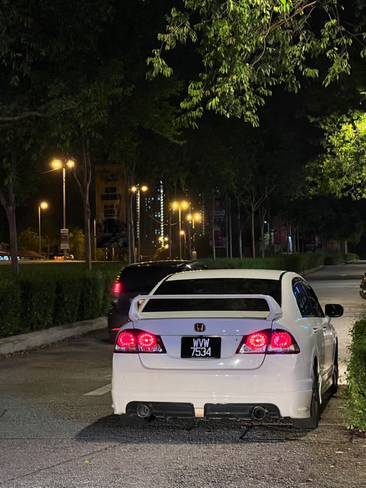 a white car is parked on the side of the road at night with its trunk open