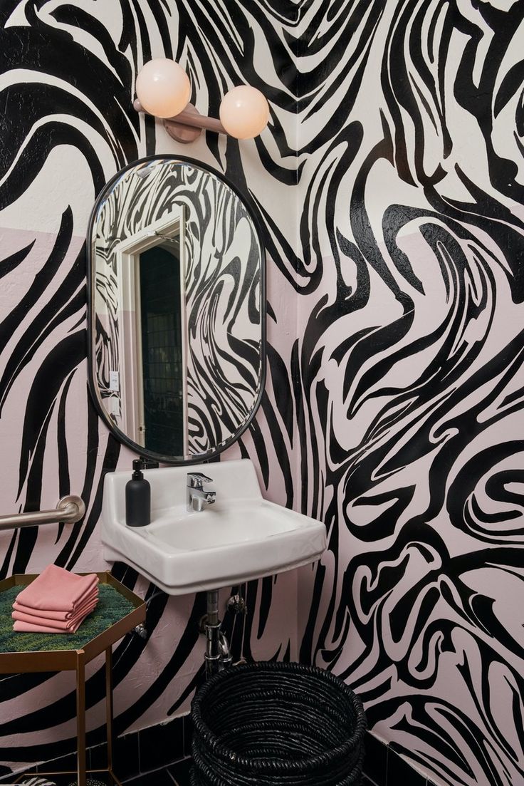 a bathroom with black and white wallpaper, a sink and mirror on the wall