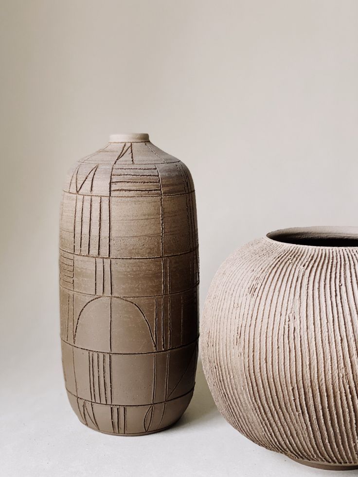 two vases sitting next to each other on a white surface with lines drawn across them