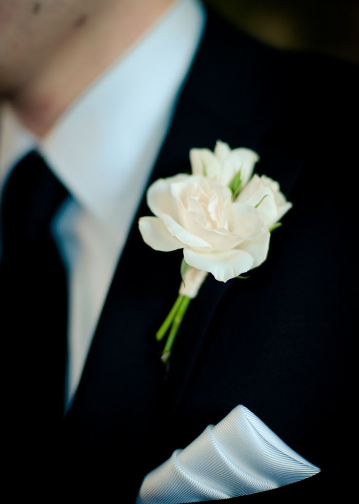 a man wearing a suit and tie with a white flower on his lapel pin