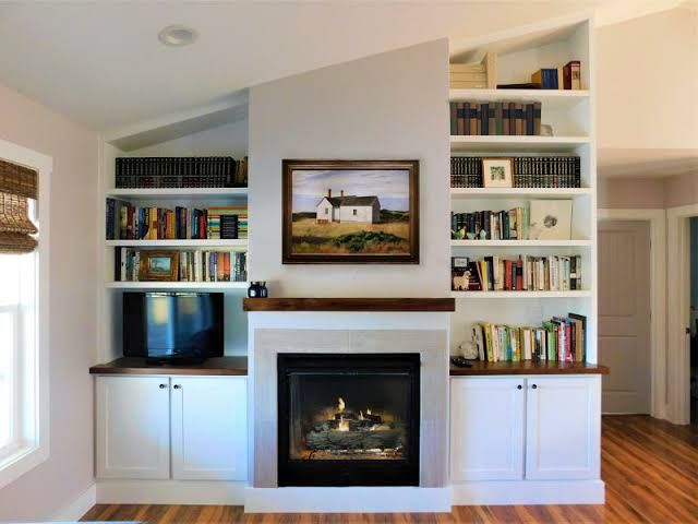 a living room filled with furniture and a fire place in front of a book shelf