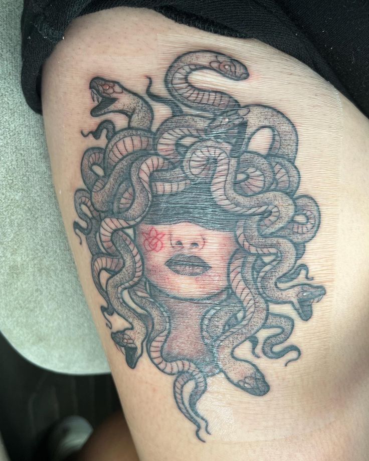 a woman's thigh with a snake tattoo on her head and an octopus around her neck