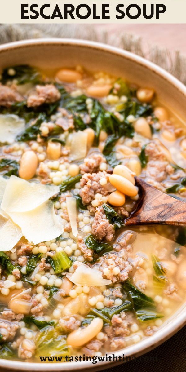 a white bowl filled with sausage and spinach soup on top of a wooden table