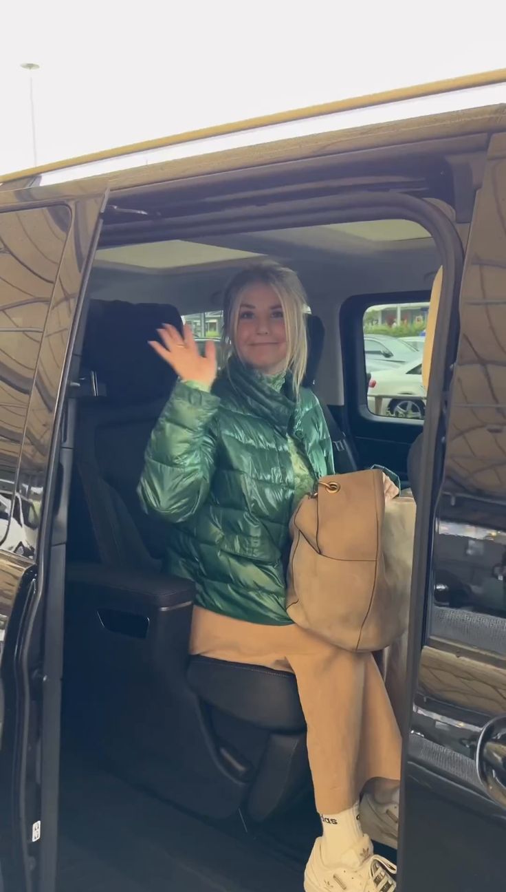 a woman sitting in the back of a vehicle waving