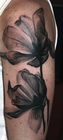 a black and white photo of a flower on someone's left arm with ink