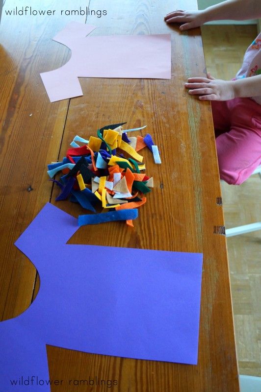 the child is cutting out paper shapes on the table