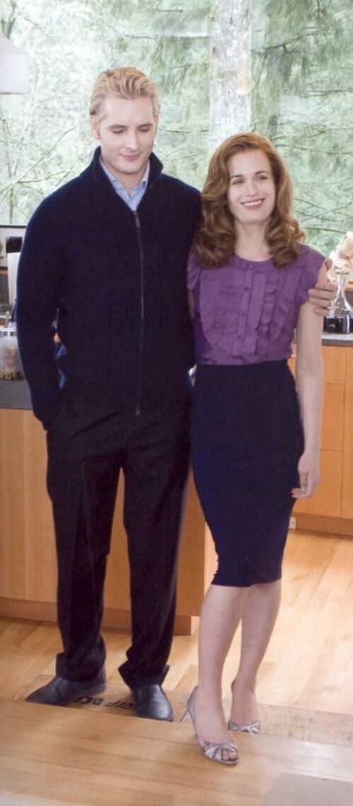 two people standing next to each other in front of a kitchen counter with wooden floors