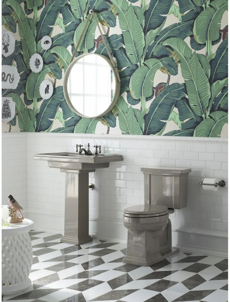 a bathroom with green and white wallpaper, checkered flooring and two toilets