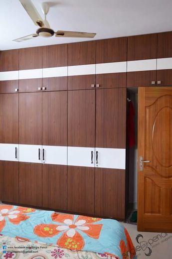 a bedroom with wooden cabinets and a bed in the foreground is a ceiling fan