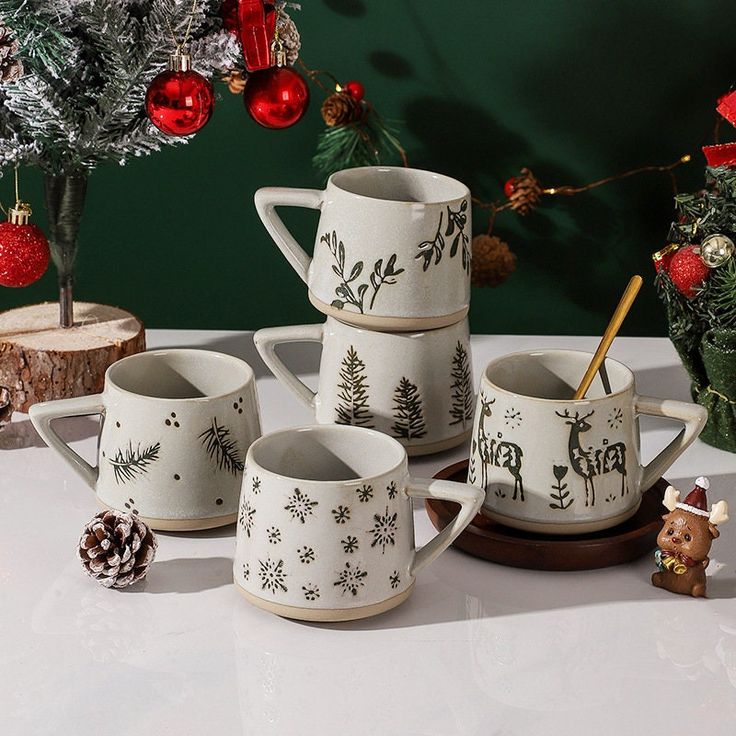 a group of coffee mugs sitting on top of a table next to christmas decorations