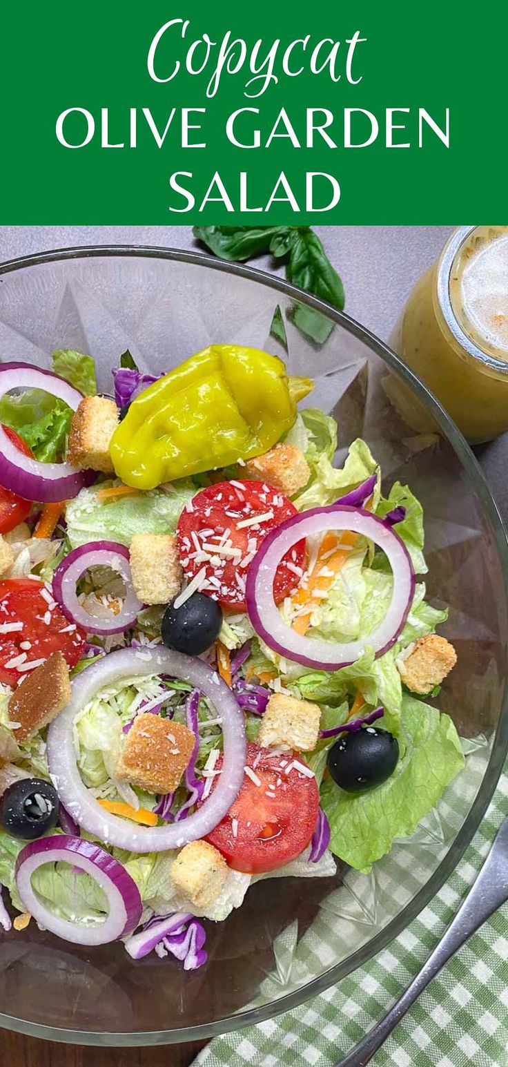 a salad with olives, tomatoes and onions in a glass bowl on a table