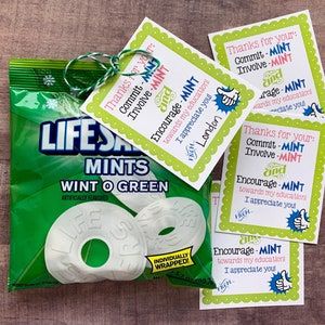 three white donuts sitting next to each other on top of a wooden table with green tags