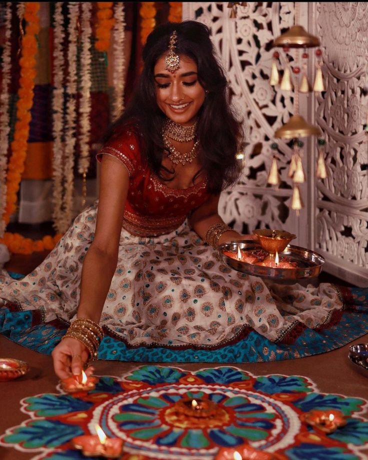 a woman sitting on the floor in front of a decorated table with plates and candles