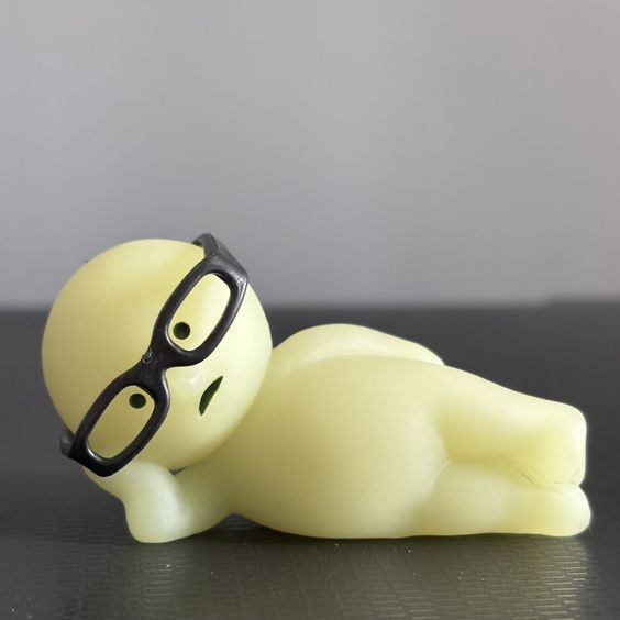 a small toy with glasses laying on top of it's back and eyes closed