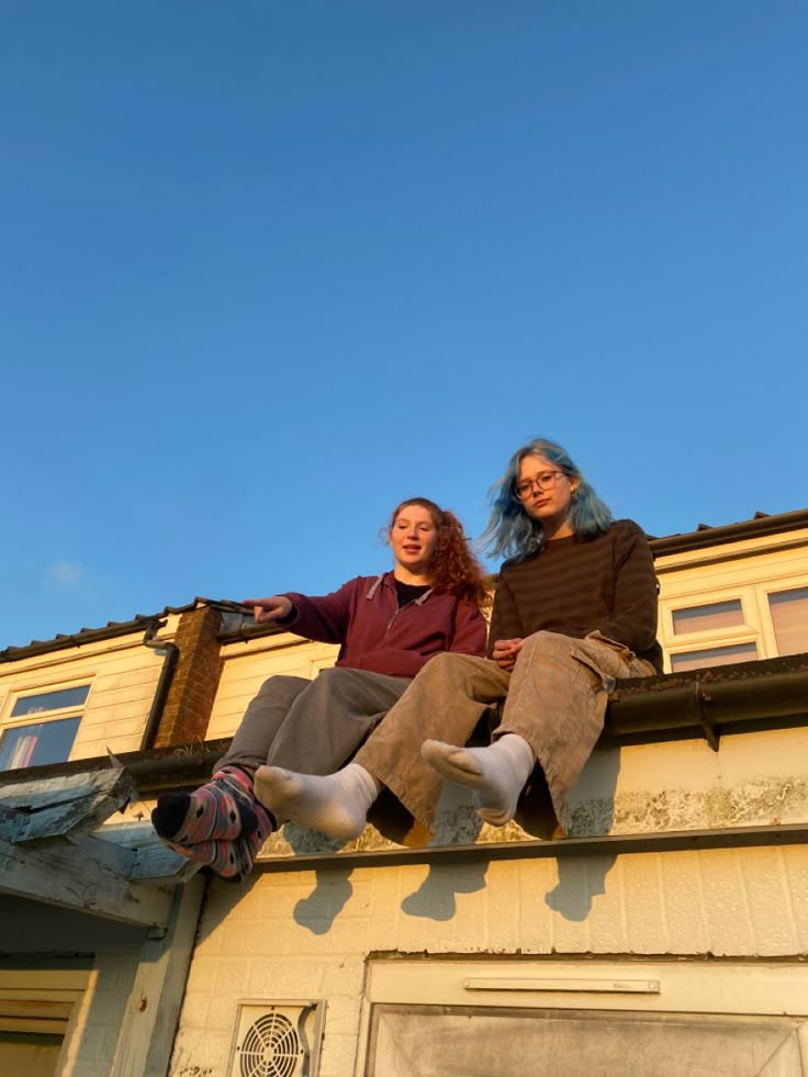 two women sitting on the roof of a building