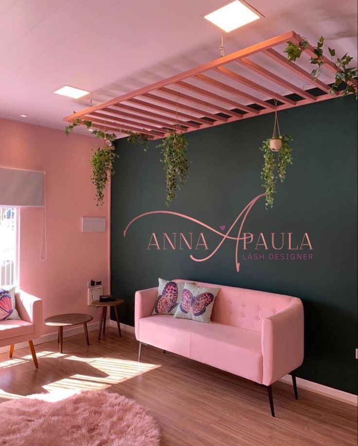 a living room with pink furniture and hanging plants on the green wall above it, along with wooden flooring