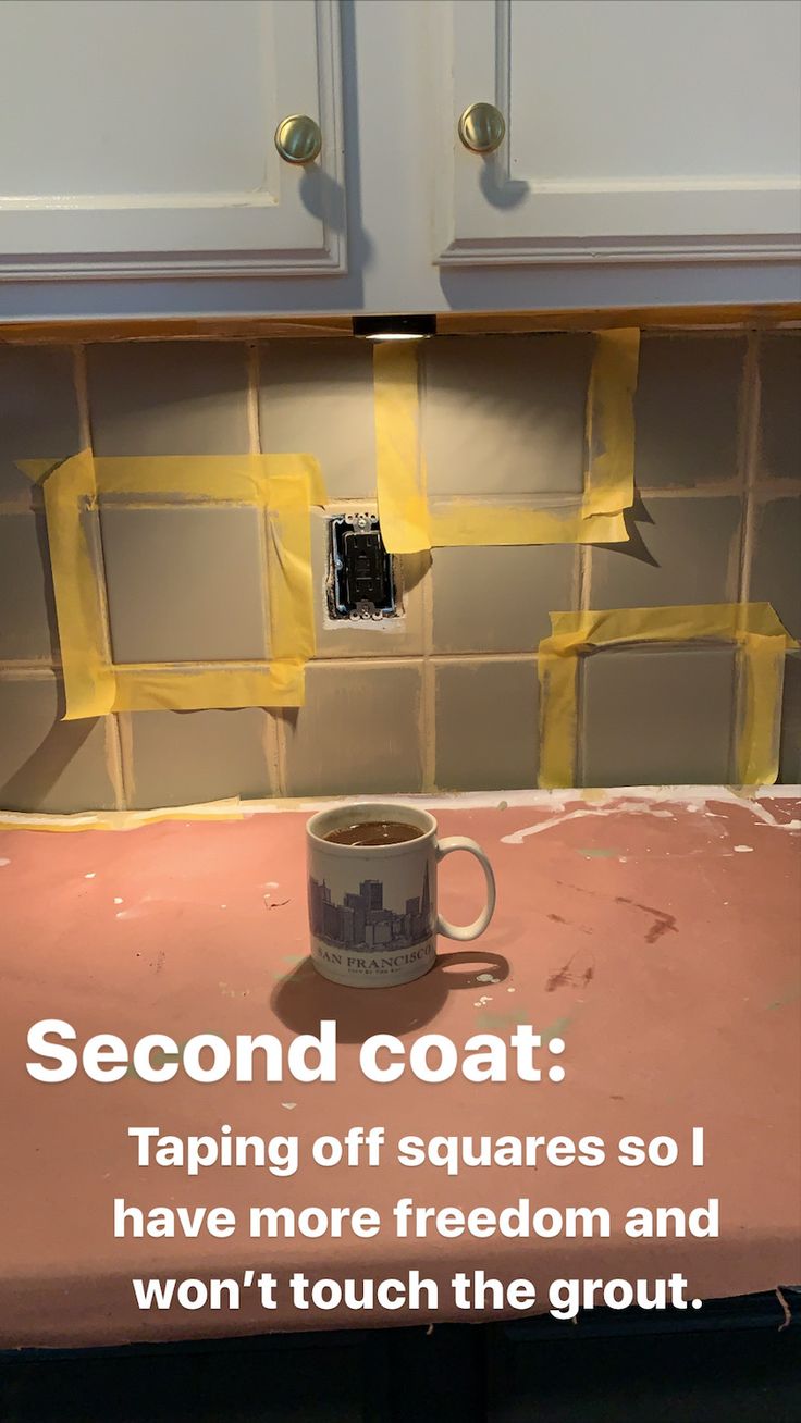 a coffee cup sitting on top of a pink counter next to a white cabinet with yellow tape