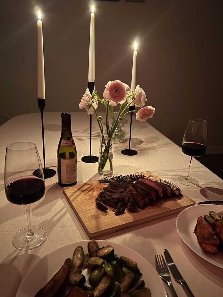 a dinner table with wine, food and candles